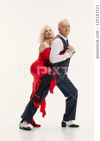 Passion and love through years. Elderly couple, woman in red dress and man in black suit, dancing tango isolated on white background 120183521