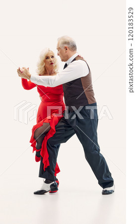 Elegant elderly couple, man and woman dressed in stylish matching dance costumes, dancing tango with passion and energy isolated on white background Elegant elderly couple, man and woman dressed in stylish matching dance costumes, dancing tango with passion and energy isolated on white background 120183529