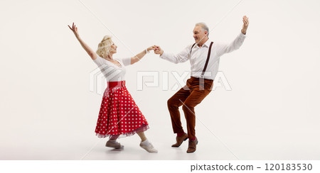 Cheerful elderly couple dancing together, woman in red polka dot skirt and man in suspenders isolated on white background 120183530