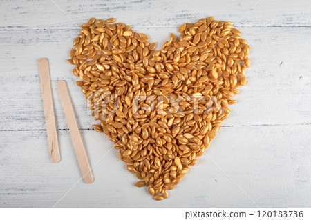 Yellow depilation wax granules in the shape of a heart on a wooden background. Intimacy and beauty Yellow depilation wax granules in the shape of a heart on a wooden background. Intimacy and beauty 120183736