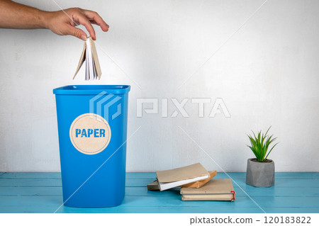 Paper sorting and recycling. Man's hand throws a book in a blue trash can 120183822