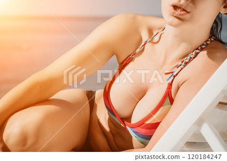 Woman in rainbow bikini. Happy tanned well looking middle aged woman in rainbow swimsuit at seaside, blue sea water in background. Holiday, vacation and recreational concept. Woman in rainbow bikini. Happy tanned well looking middle aged woman in rainbow swimsuit at seaside, blue sea water in background. Holiday, vacation and recreational concept. 120184247