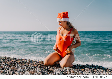 Woman in Red Swimsuit with Santa Hat on Beach Woman in Red Swimsuit with Santa Hat on Beach 120184249