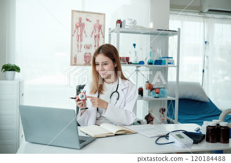 A woman doctor is pointing at a medical model on a laptop 120184488