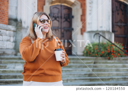 Happy young 30s Woman in sunglasses talking on phone with eco paper cup of coffee on urban background, Coffee to go on the city street. Food, rest, Take away, technology concept. Phone Communication. 120184550