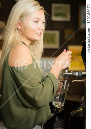 Young woman dispensing beer in bar from spigot Young woman dispensing beer in bar from spigot 120184673