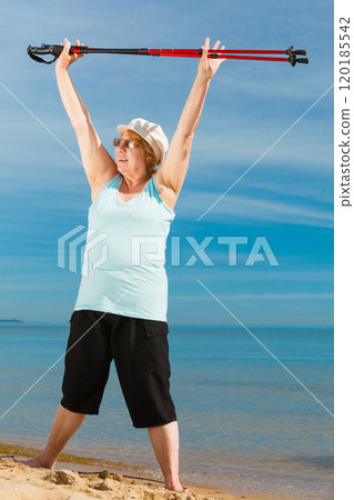 Senior woman warming up with walking poles 120185542