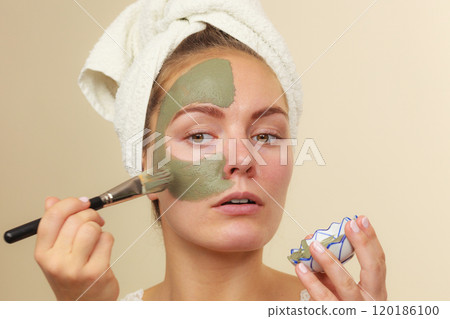 Woman applying with brush clay mud mask to her face 120186100