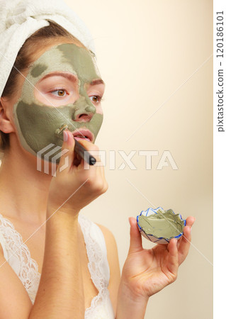 Woman applying with brush clay mud mask to her face Woman applying with brush clay mud mask to her face 120186101