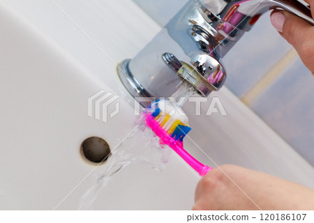 Hand holding toothbrush in bathroom 120186107
