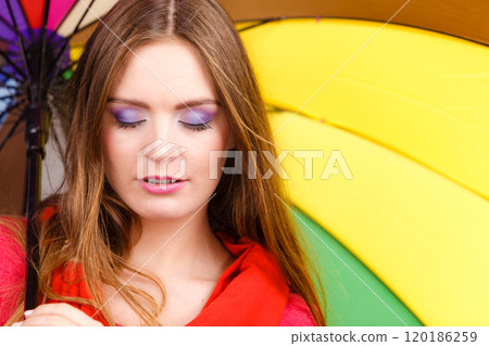 Woman standing under multicolored umbrella 120186259
