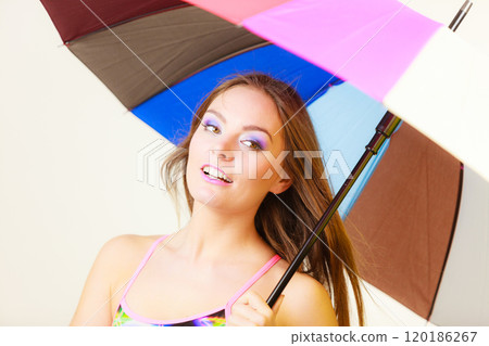 Woman standing under colorful rainbow umbrella 120186267