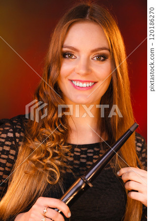 Happy woman curling her long brown hair 120186270