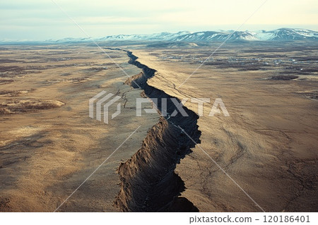 Deep canyon dividing the vast icelandic plains near a distant town 120186401