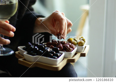 Christmas and New Year snacks. Hands holding a plate in the shape of a Christmas tree with olives. 120186810