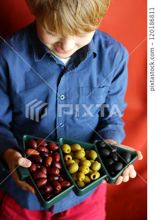 Christmas and New Year snacks. Hands holding a plate in the shape of a Christmas tree with olives. 120186811