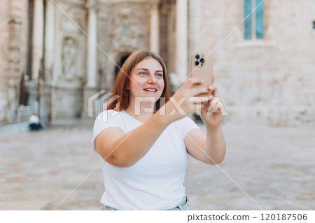 Happy redhead woman making selfie photo on urban background. Use technology concept, Traveling Europe in summer. Attractive female tourist is exploring new city in Spain Happy redhead woman making selfie photo on urban background. Use technology concept, Traveling Europe in summer. Attractive female tourist is exploring new city in Spain 120187506