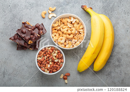 Cashews, peanuts, bananas and chocolate with hazelnuts representing magnesium rich food top view 120188824