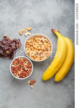 Cashews, peanuts, bananas and chocolate with hazelnuts representing magnesium rich food top view 120188828