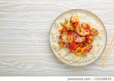 Chicken stir fry with peppers and rice on a plate with chopsticks top view, space for text Chicken stir fry with peppers and rice on a plate with chopsticks top view, space for text 120188830