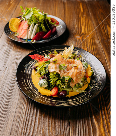 Elegant duo of gourmet salads with smoked salmon, fresh greens, and ingredients on wooden table Elegant duo of gourmet salads with smoked salmon, fresh greens, and ingredients on wooden table 120189059