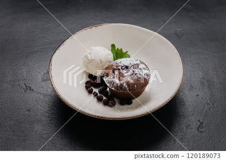 Decadent chocolate lava cake with vanilla ice cream, berries, and mint on a rustic plate 120189073