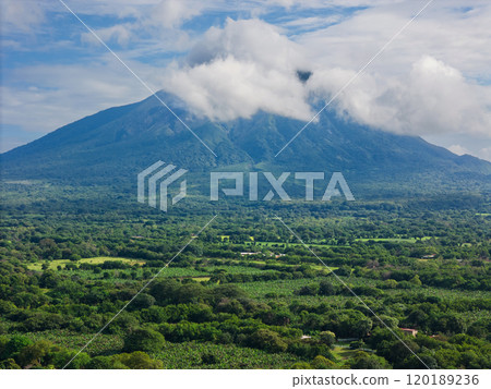 Lush green landscape beneath a majestic volcano Lush green landscape beneath a majestic volcano 120189236