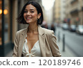 A young woman with a chic bob haircut is smiling brightly while wearing a fashionable beige blazer over a white top. The urban street scene in the background adds a lively atmosphere, highlighting her 120189746