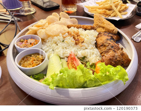 mixed fried and grilled chicken rice, traditional indonesian cuisine called nasi campur comprise of fried or grilled chicken served with local salad and chili paste and also crackers, delicious mixed fried and grilled chicken rice, traditional indonesian cuisine called nasi campur comprise of fried or grilled chicken served with local salad and chili paste and also crackers, delicious 120190373