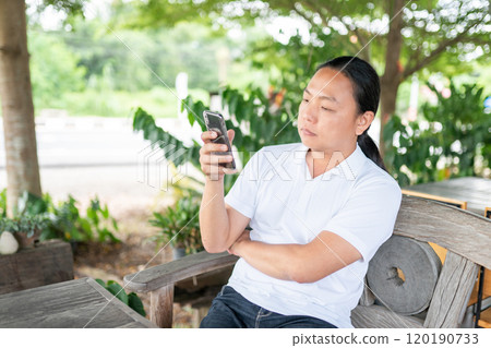 Person is playing and touch screen telephone. Telephone is a modern communication technology. Portrait of person is sitting, looking and touching mobile phones. 120190733