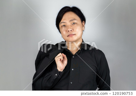 The portrait of a young Asian man wearing the tidy black suit with plain expression on the white grey background shot in the studio. The portrait of a young Asian man wearing the tidy black suit with plain expression on the white grey background shot in the studio. 120190753