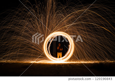 Spinning and burning Steel wool sparkle fire in the circle shape with long speed shutter shoot glowing light line to the ground. Spinning and burning Steel wool sparkle fire in the circle shape with long speed shutter shoot glowing light line to the ground. 120190843