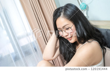 Asian Glasses Woman relax on her bed in the morning at her bedroom. 120191444