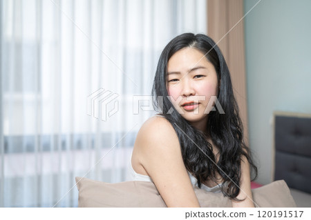 Asian Woman is posing with her sexy shoulder on her bed in the bedroom. 120191517
