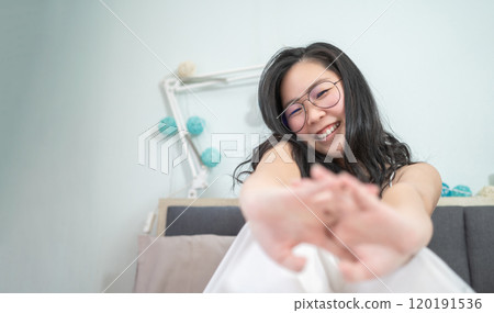 Asian young glasses woman stretches oneself on her bed in the morning. 120191536