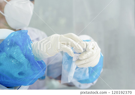 Close up to the rubber gloves on the asian medical staff is processing coronavirus or covid-19 test in the negative room pressure. Close up to the rubber gloves on the asian medical staff is processing coronavirus or covid-19 test in the negative room pressure. 120192370