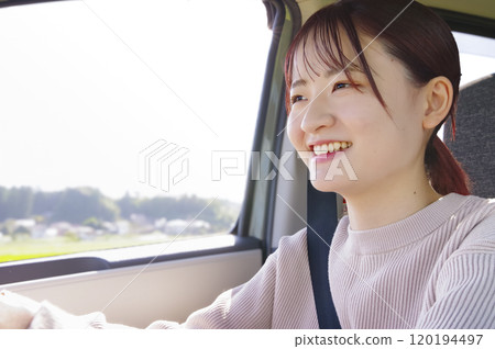 Smiling young woman driving 120194497
