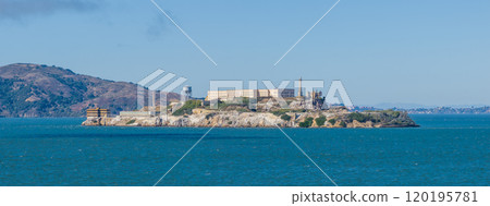 Alcatraz Island features the historic penitentiary and watchtower, surrounded by San Francisco Bay's blue waters and Marin Headlands in the background. 120195781