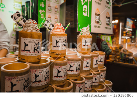 A vibrant street food stall in Shanghai features bamboo cups of soft serve ice cream with panda decorations. Colorful signage and a bustling market scene are visible. 120195803