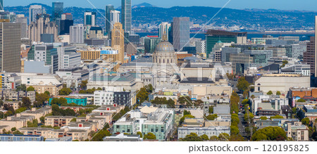 Aerial view of San Francisco featuring City Hall's dome, historic and modern skyscrapers like Salesforce Tower, and the Bay Bridge in the background. 120195825