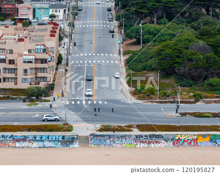 A street in San Francisco features a long road with residential buildings, lush greenery, and a colorful graffiti covered wall in the foreground. A street in San Francisco features a long road with residential buildings, lush greenery, and a colorful graffiti covered wall in the foreground. 120195827