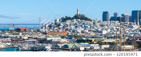San Francisco's urban landscape with Coit Tower on Telegraph Hill, Bay Bridge in the background, and a vibrant waterfront and marina in the foreground. 120195971