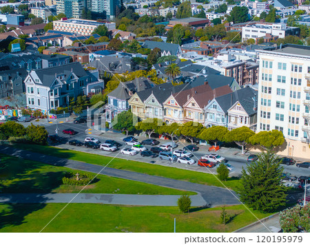 The image features the Painted Ladies, colorful Victorian houses, with modern city buildings in the background and Alamo Square Park in the foreground. 120195979
