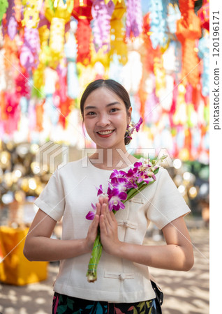 A charming Asian woman stands in a temple with colorful lanterns in the background. A charming Asian woman stands in a temple with colorful lanterns in the background. 120196171