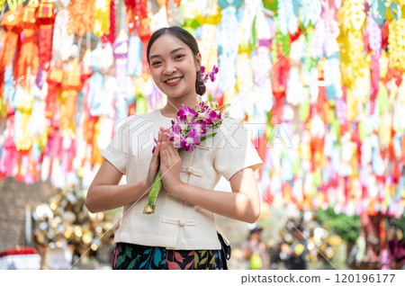 A charming Asian woman stands in a temple with colorful lanterns in the background. A charming Asian woman stands in a temple with colorful lanterns in the background. 120196177