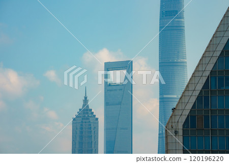View of Shanghai's skyline featuring Jin Mao Tower, Shanghai World Financial Center, and Shanghai Tower against a clear blue sky. 120196220