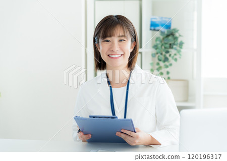 A woman at the reception desk wearing a white coat A woman at the reception desk wearing a white coat 120196317