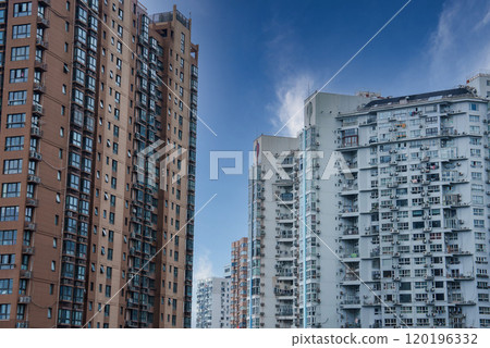 Cluster of modern high rise residential buildings in Shanghai, China, featuring brown and light gray facades, numerous balconies, and a clear blue sky. Cluster of modern high rise residential buildings in Shanghai, China, featuring brown and light gray facades, numerous balconies, and a clear blue sky. 120196332