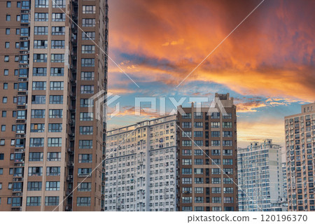 High rise residential buildings in Shanghai under a dramatic sunset sky, featuring modern architecture with numerous windows and balconies. High rise residential buildings in Shanghai under a dramatic sunset sky, featuring modern architecture with numerous windows and balconies. 120196370