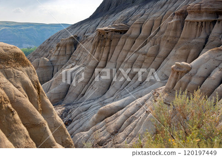 Canyon in badlands with eroded formations on the hills in summer. 120197449